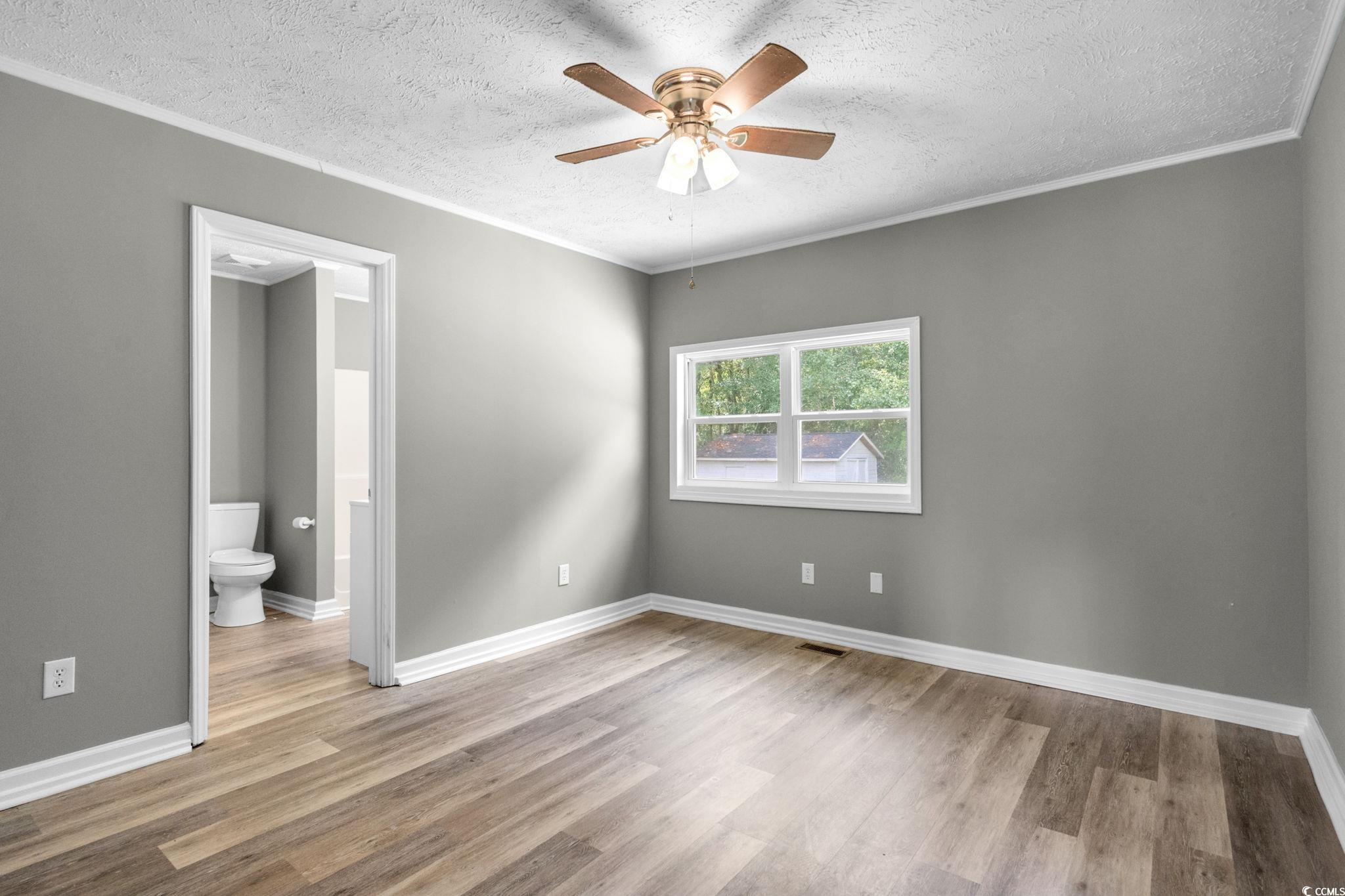450 Highway 348 Loris, SC 29569 - Photo 17 of 37 Unfurnished bedroom featuring ornamental molding, light wood-type flooring, a textured ceiling, ceiling fan, and connected bathroom