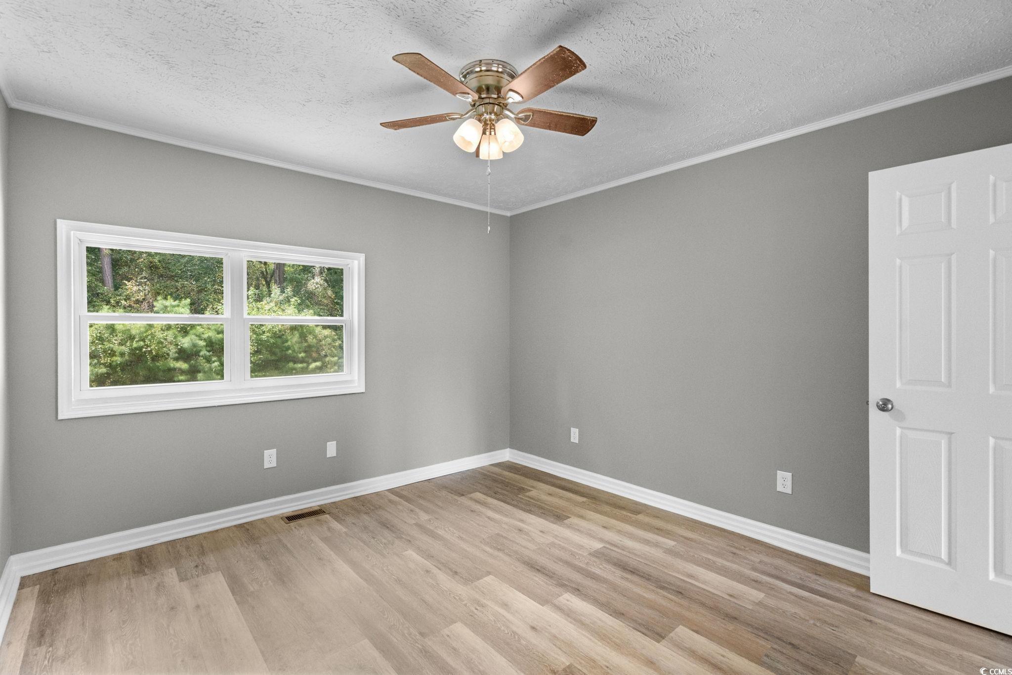 450 Highway 348 Loris, SC 29569 - Photo 18 of 37 Spare room featuring a textured ceiling, ornamental molding, light wood-type flooring, and a ceiling fan