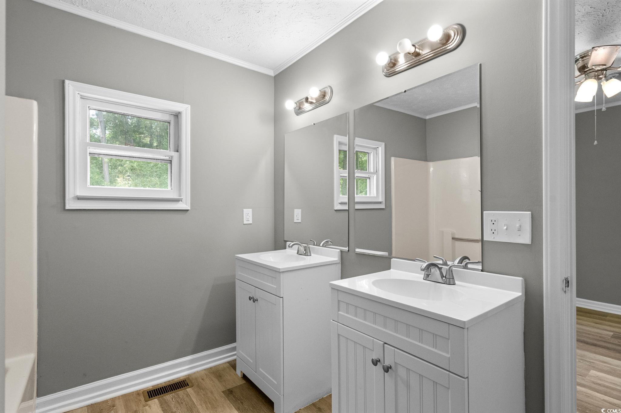 450 Highway 348 Loris, SC 29569 - Photo 20 of 37 Bathroom featuring light wood-type flooring, ornamental molding, two vanities, a textured ceiling, and ceiling fan