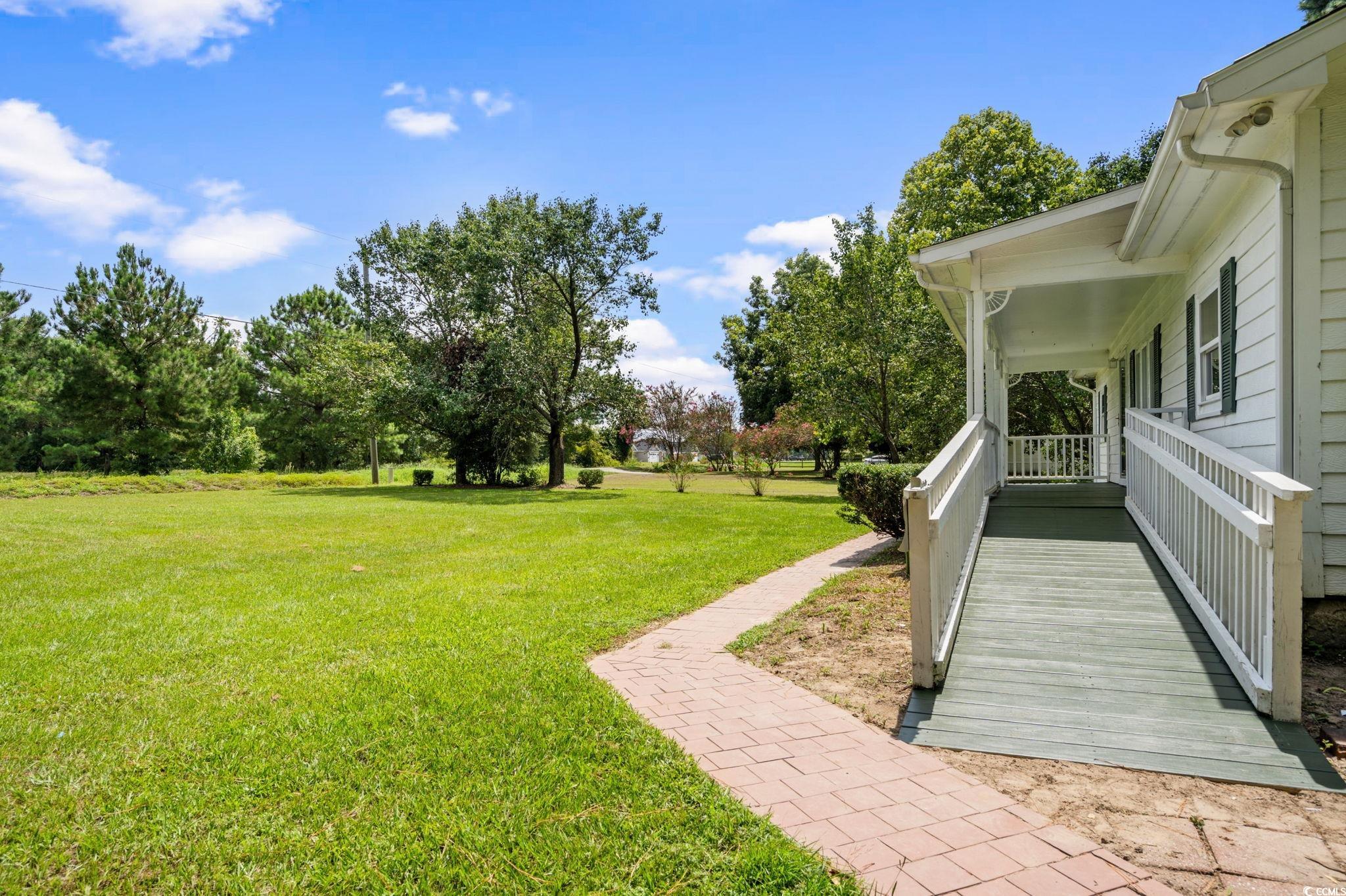 450 Highway 348 Loris, SC 29569 - Photo 2 of 37 View of grassy yard with a porch and view of scattered trees