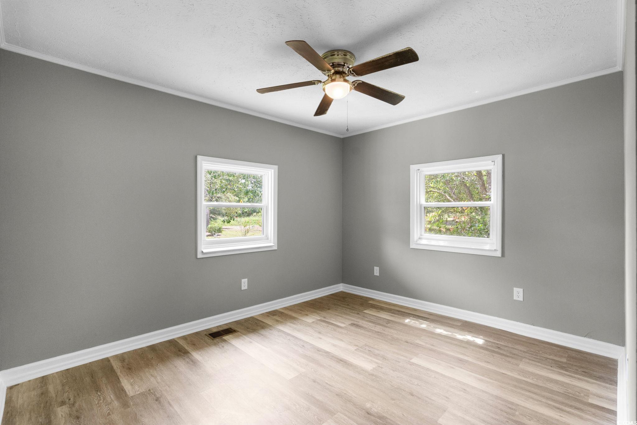 450 Highway 348 Loris, SC 29569 - Photo 22 of 37 Empty room with ornamental molding, light wood finished floors, a textured ceiling, and ceiling fan