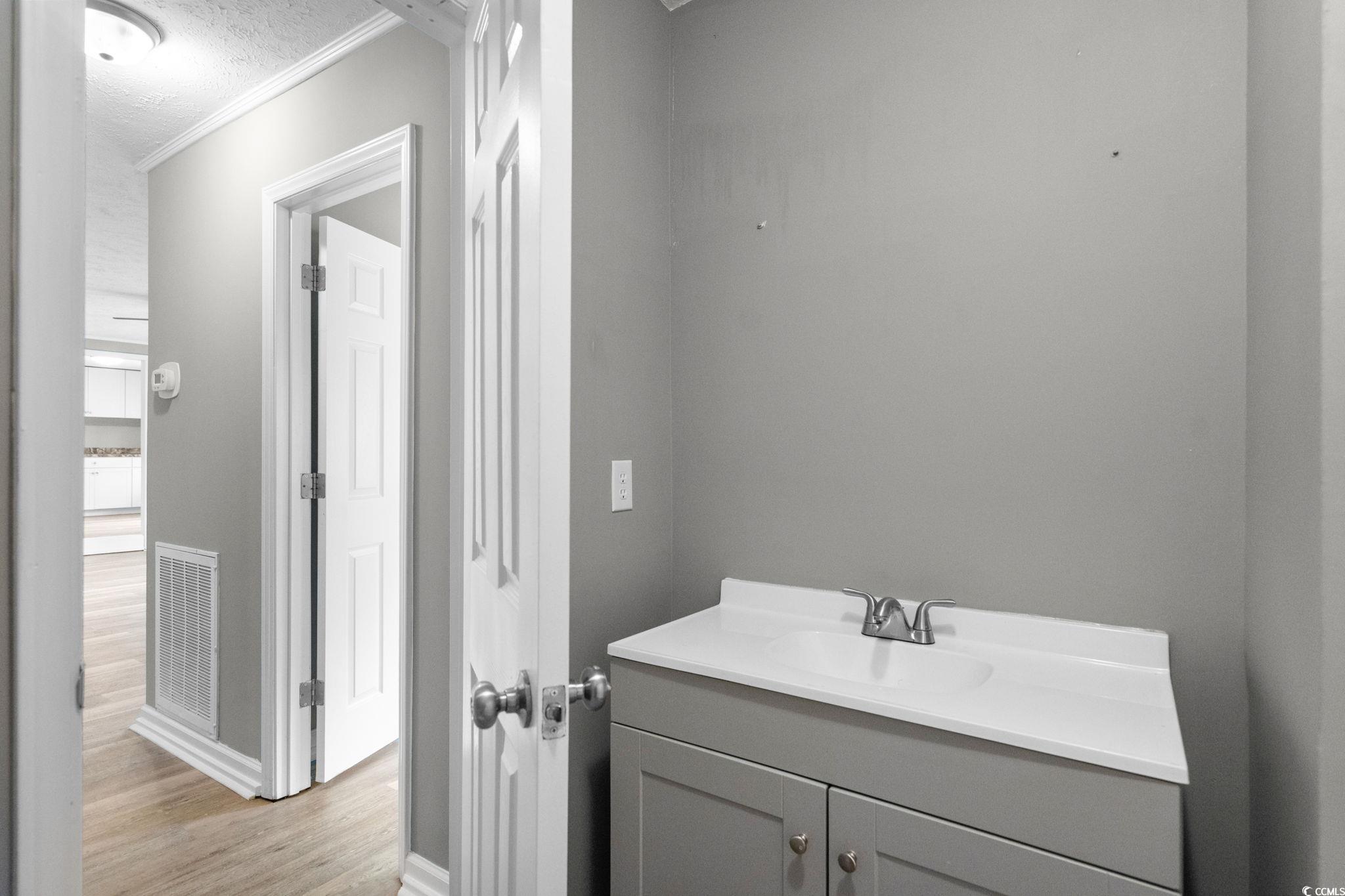 450 Highway 348 Loris, SC 29569 - Photo 24 of 37 Bathroom with vanity, light wood-style flooring, ornamental molding, and a textured ceiling