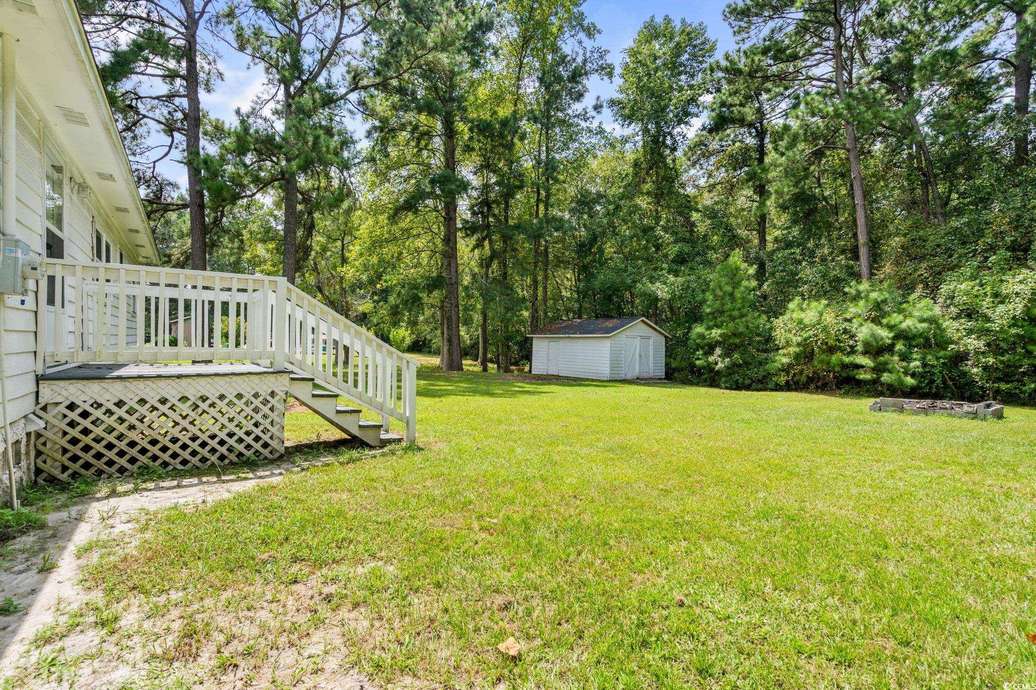 450 Highway 348 Loris, SC 29569 - Photo 28 of 37 View of green lawn with stairs, a deck, view of wooded area, and a storage unit