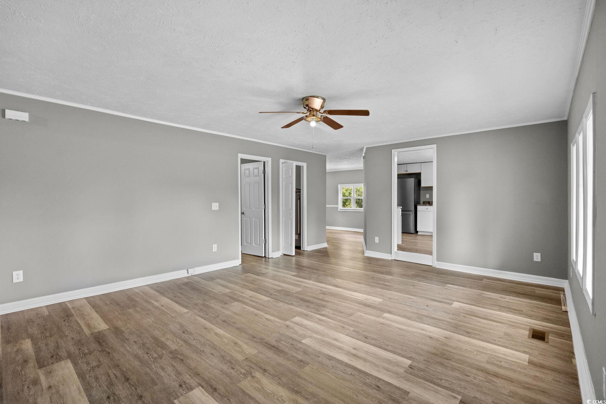 450 Highway 348 Loris, SC 29569 - Photo 6 of 37 Unfurnished living room featuring a textured ceiling, light wood-style flooring, a ceiling fan, and crown molding