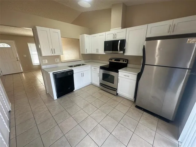 a kitchen with stainless steel appliances granite countertop a refrigerator stove a sink and a microwave