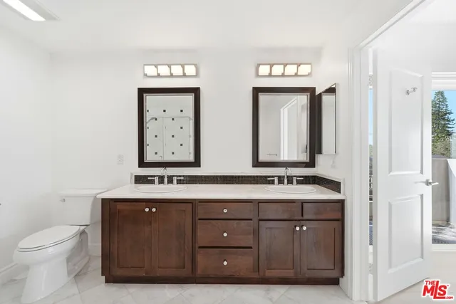 a bathroom with double vanity sinks a toilet and a mirror