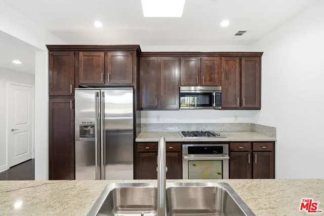 a kitchen with stainless steel appliances granite countertop a refrigerator and a sink