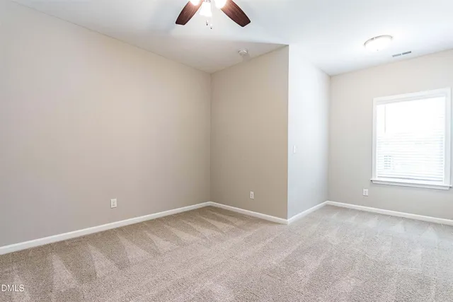 an empty room with chandelier fan and window