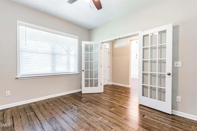 a view of empty room with wooden floor and fan