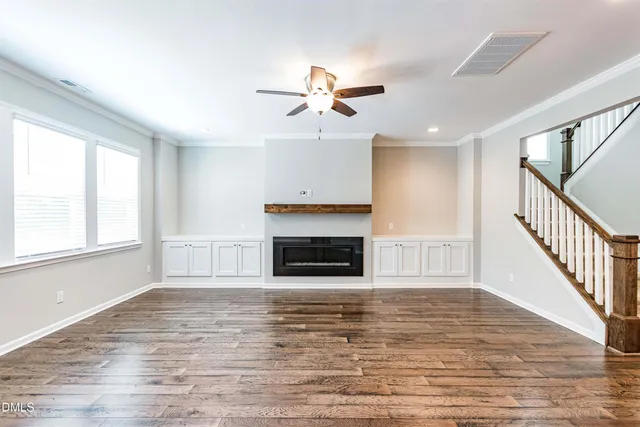 a view of a livingroom with a fireplace a ceiling fan and wooden floor