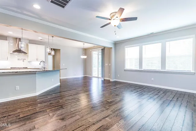 a view of an empty room with window and wooden floor