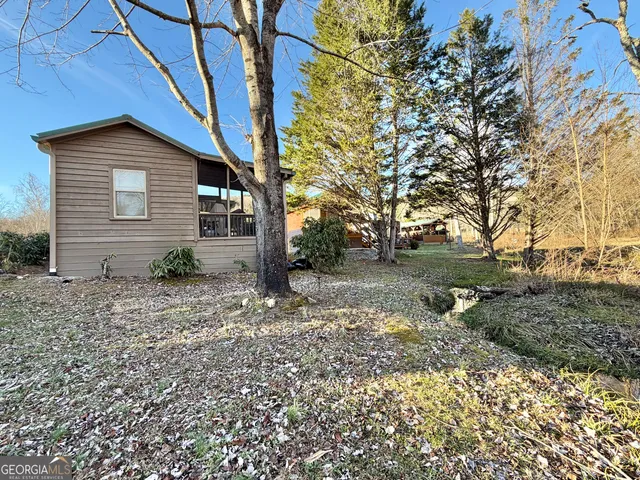 a backyard of a house with plants and large tree
