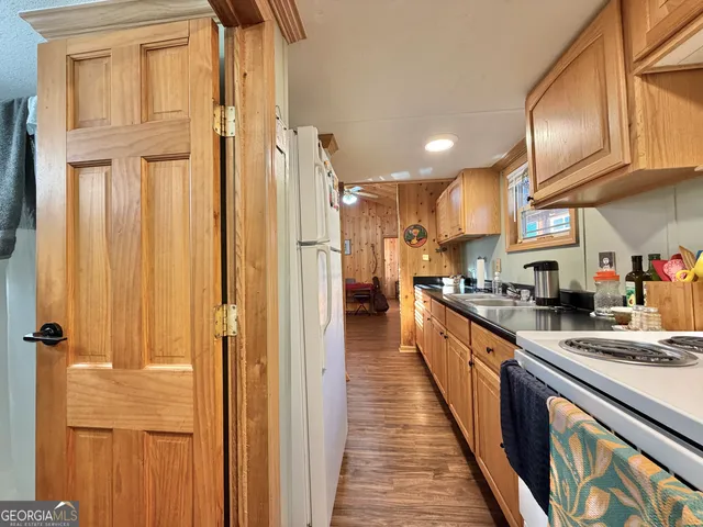 a large kitchen with stainless steel appliances granite countertop a refrigerator a sink dishwasher and wooden cabinets with wooden floor