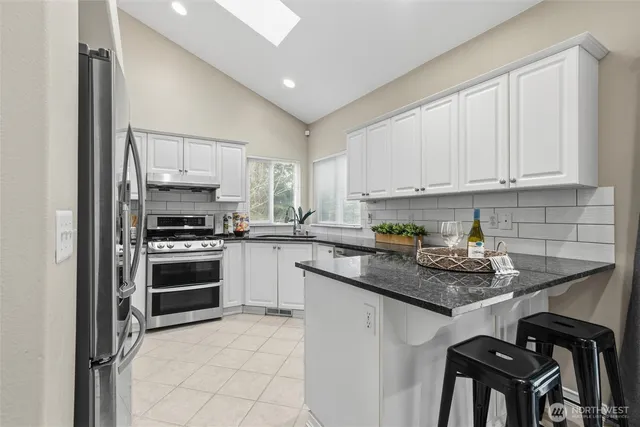 a kitchen with a stove a sink and white cabinets