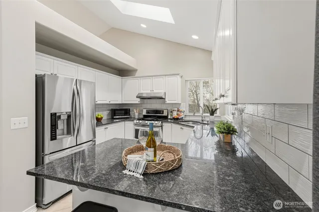 a kitchen with stainless steel appliances granite countertop a sink refrigerator stove and microwave