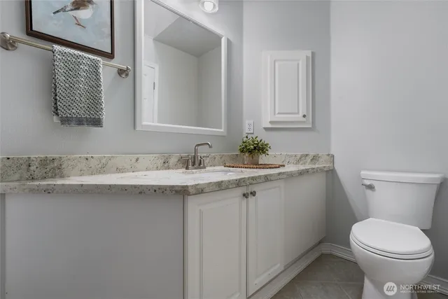 a bathroom with a granite countertop toilet sink and mirror