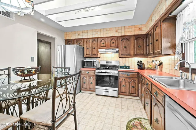 a kitchen with stainless steel appliances a stove a sink cabinets and a dining table