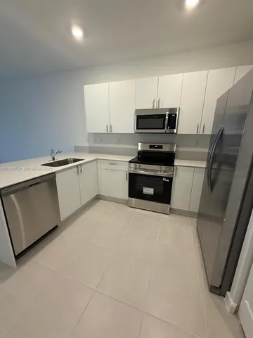 a kitchen with granite countertop a refrigerator sink and stove
