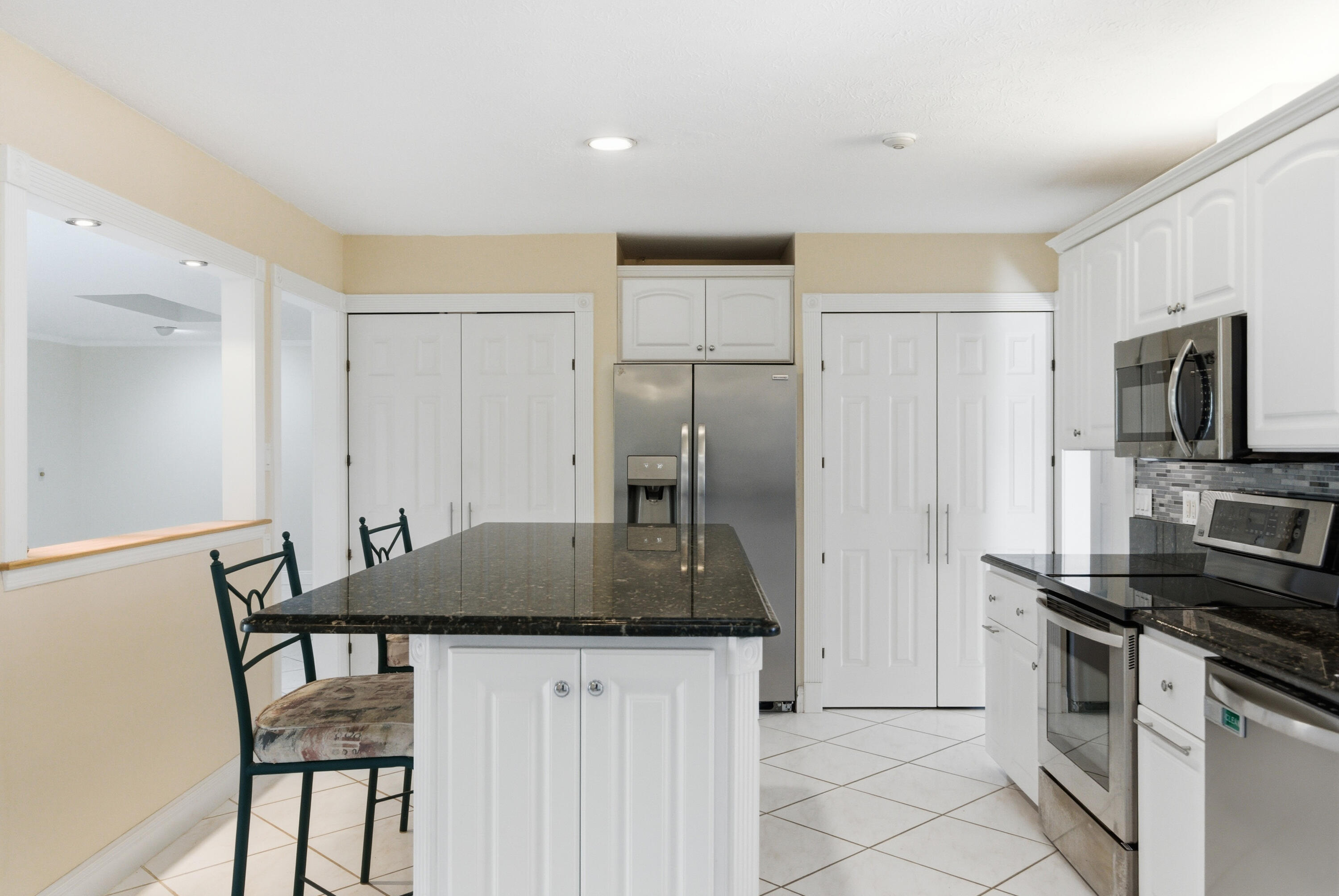 5151 Southeast Burning Tree Circle Stuart, FL 34997 - Photo 11 of 74 a kitchen with stainless steel appliances granite countertop a stove refrigerator and a refrigerator with white cabinets