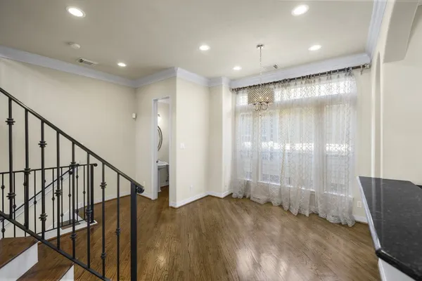 a view of an empty room with wooden floor and staircase