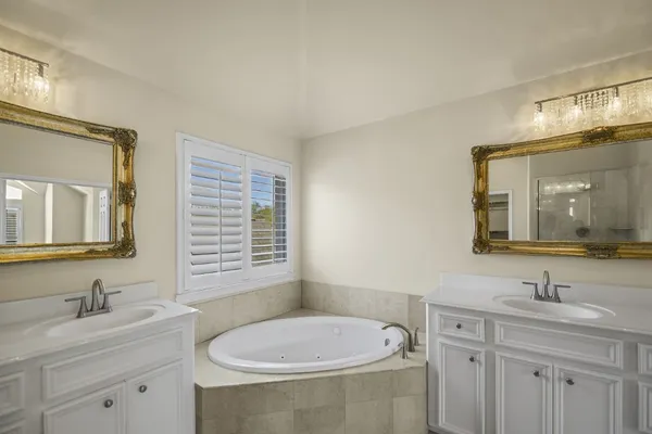 a bathroom with a sink double vanity granite tub and a mirror