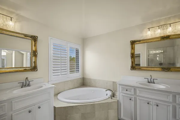 a bathroom with a sink double vanity granite tub and a mirror
