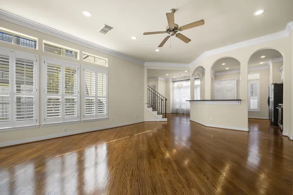 a view of a big room with wooden floor a ceiling fan and windows