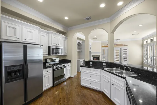 a large kitchen with stainless steel appliances granite countertop a stove a sink and a refrigerator