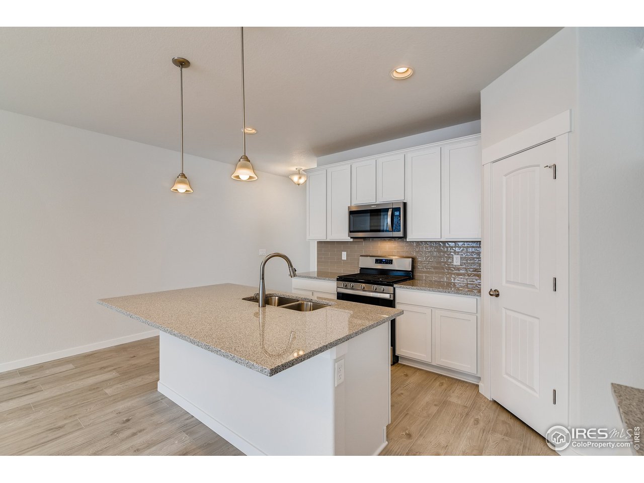 2147 Gather Drive Windsor, CO 80550 - Photo 11 of 28 a kitchen with stainless steel appliances a sink a stove a refrigerator a center island and cabinets