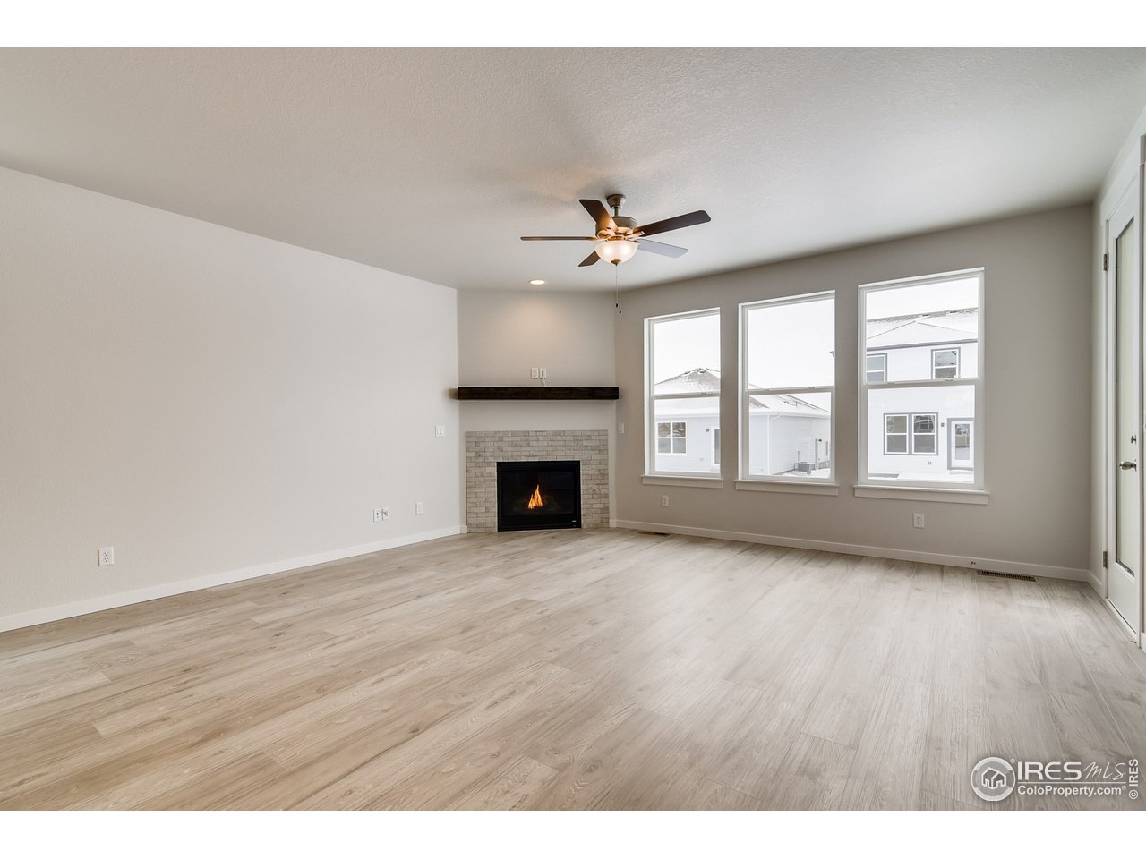 2147 Gather Drive Windsor, CO 80550 - Photo 6 of 28 an empty room with wooden floor fireplace and windows