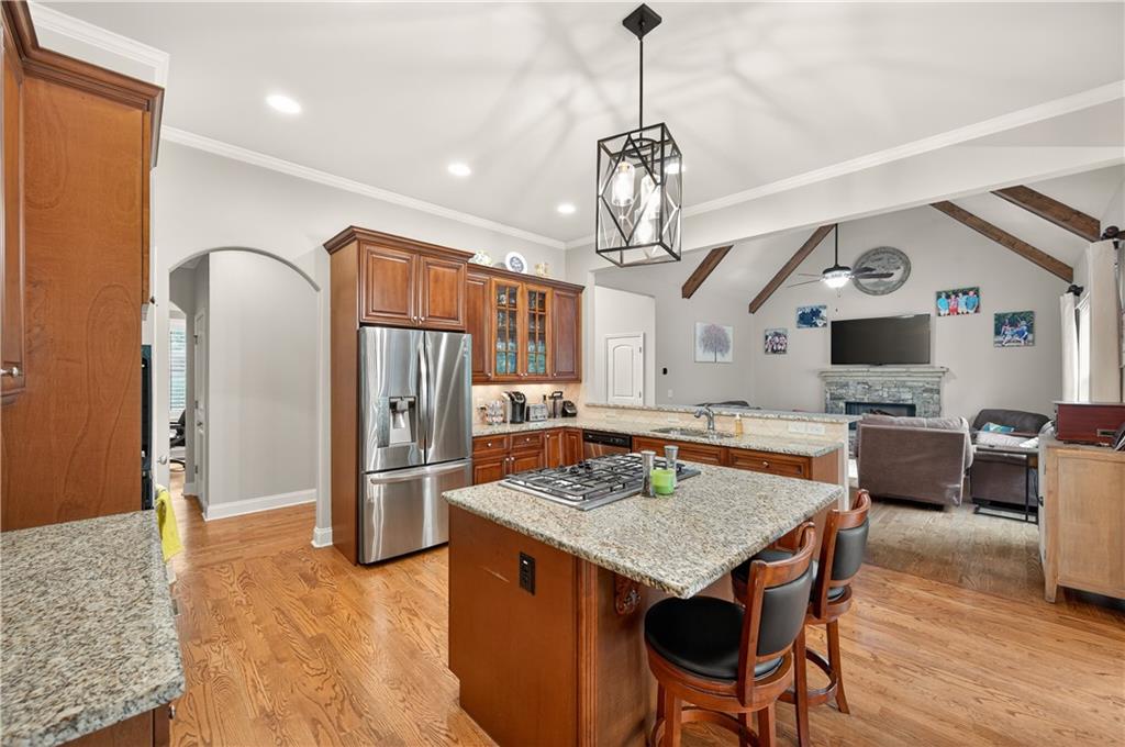 5250 Kendalls Way Cumming, GA 30041 - Photo 13 of 42 a open kitchen with stainless steel appliances granite countertop a kitchen island a stove a refrigerator a oven a dining table and chairs with wooden floor