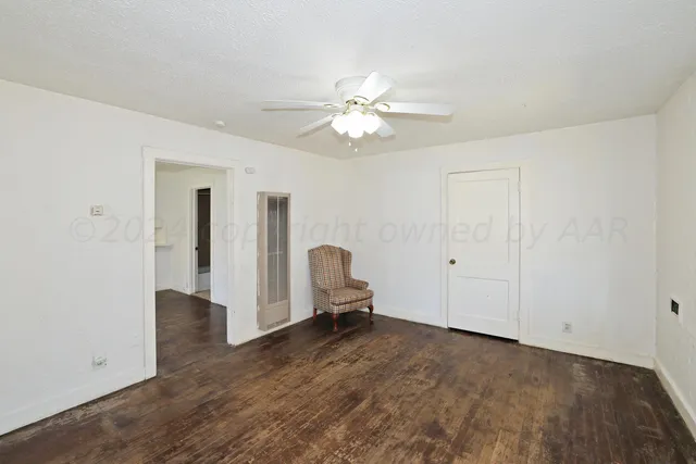 a view of an empty room with chandelier fan and a window