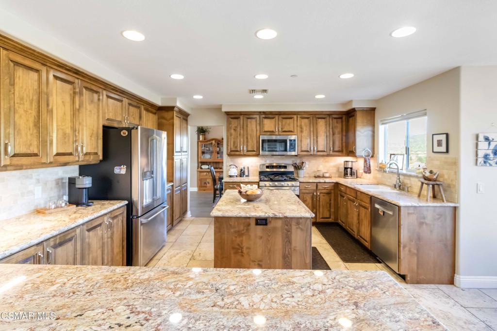 1308 Gonzales Road Simi Valley, CA 93063 - Photo 15 of 48 a large kitchen with stainless steel appliances kitchen island granite countertop a large counter top a stove a refrigerator a sink dishwasher with a dining table and chairs