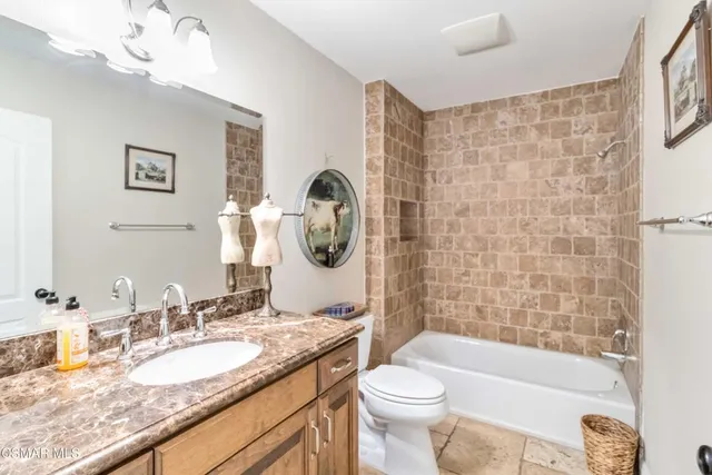 a bathroom with a granite countertop sink mirror toilet and bathtub