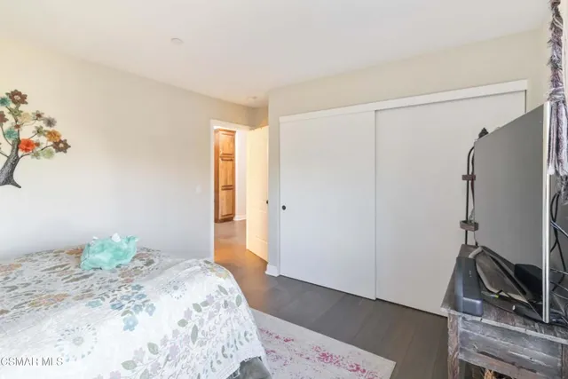 a bedroom with a bed wooden floor and a flat screen tv