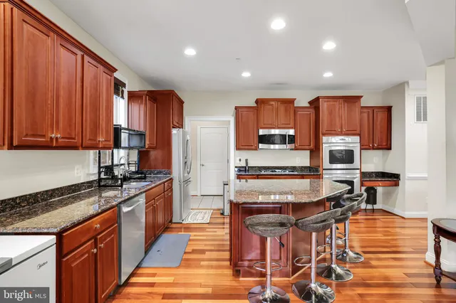 a kitchen with stainless steel appliances kitchen island granite countertop a stove top oven a sink and cabinets