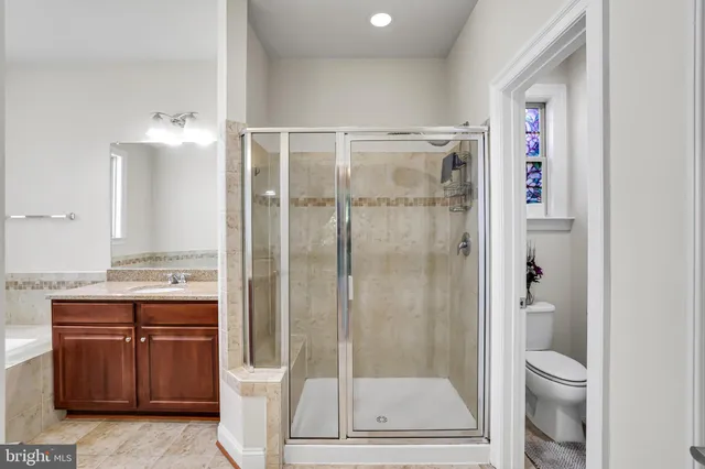 a bathroom with a granite countertop sink a toilet and shower