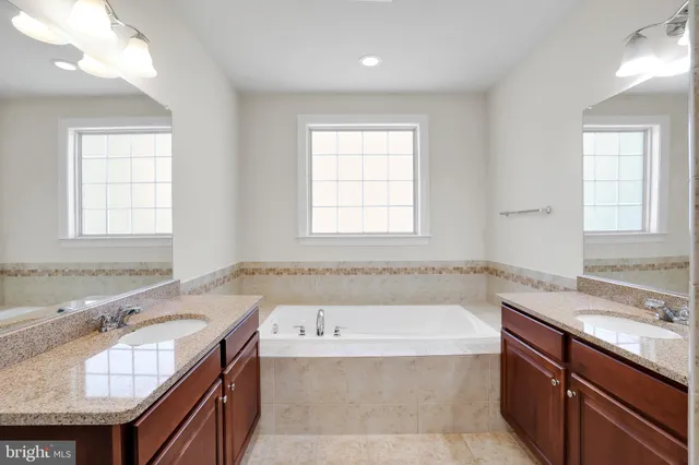 a bathroom with a granite countertop tub sink and mirror