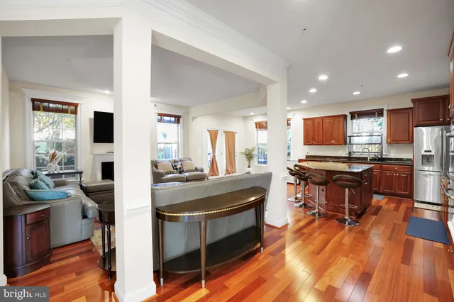 a living room with stainless steel appliances kitchen island granite countertop furniture wooden floor and a view of kitchen
