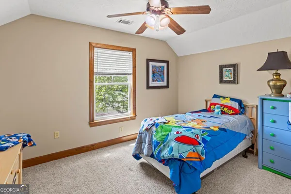 a bedroom with a bed a dresser and painting on the wall