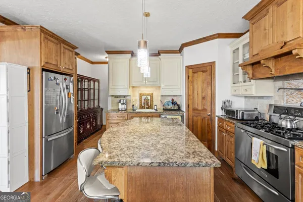a kitchen with stainless steel appliances granite countertop a refrigerator a stove and a wooden cabinets
