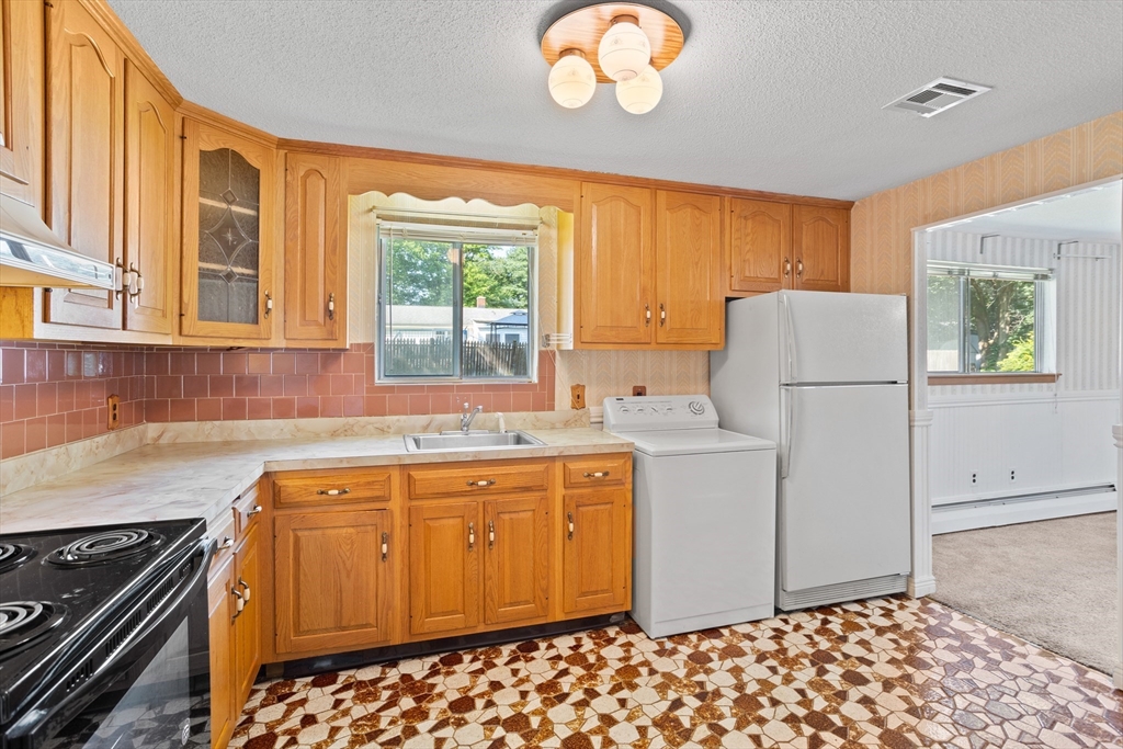 52 Brooks Street Maynard, MA 01754 - Photo 10 of 28 a kitchen with a refrigerator and a stove top oven