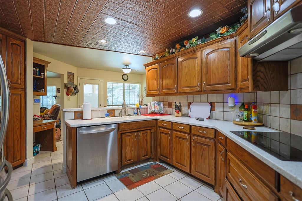 111 Deerfield Road Paradise, TX 76073 - Photo 11 of 39 Kitchen featuring an ornate ceiling, a peninsula, under cabinet range hood, stainless steel appliances, and brown cabinets