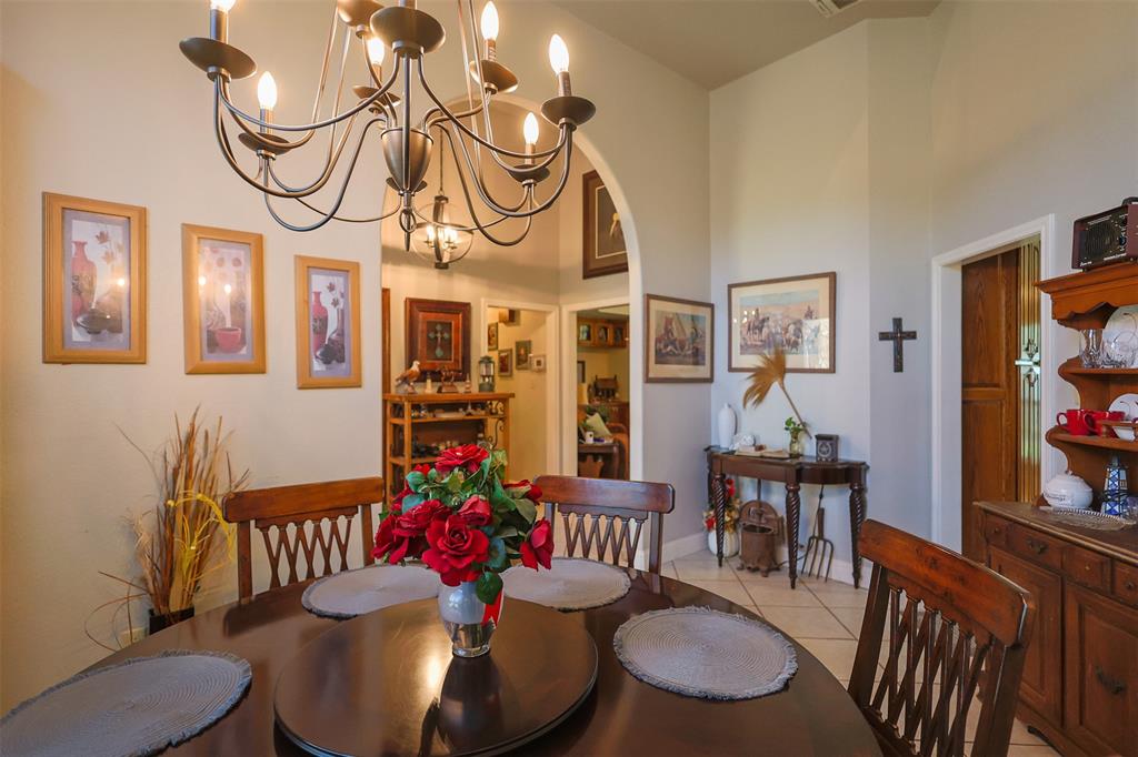 111 Deerfield Road Paradise, TX 76073 - Photo 13 of 39 Dining area featuring a chandelier, arched walkways, light tile patterned flooring, and a high ceiling