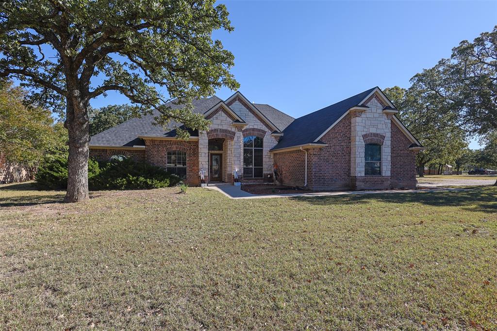 111 Deerfield Road Paradise, TX 76073 - Photo 2 of 39 French country style house with a front yard, stone siding, brick siding, and roof with shingles