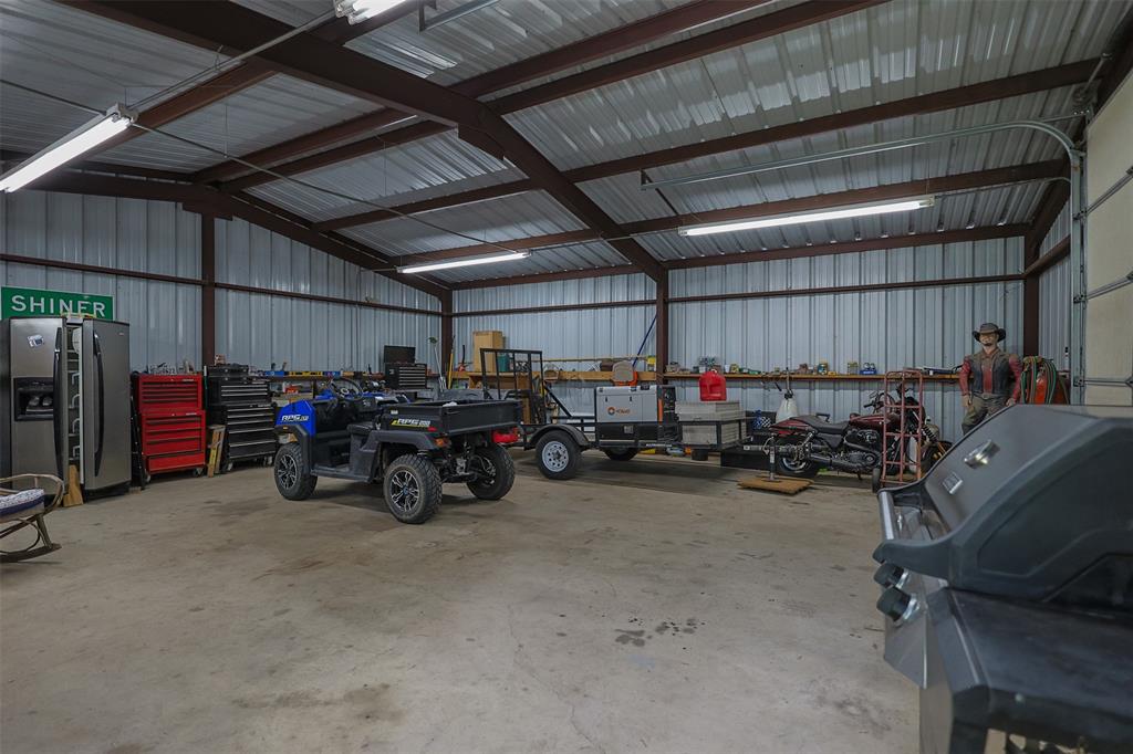 111 Deerfield Road Paradise, TX 76073 - Photo 27 of 39 Garage featuring metal wall, a workshop area, and stainless steel fridge with ice dispenser