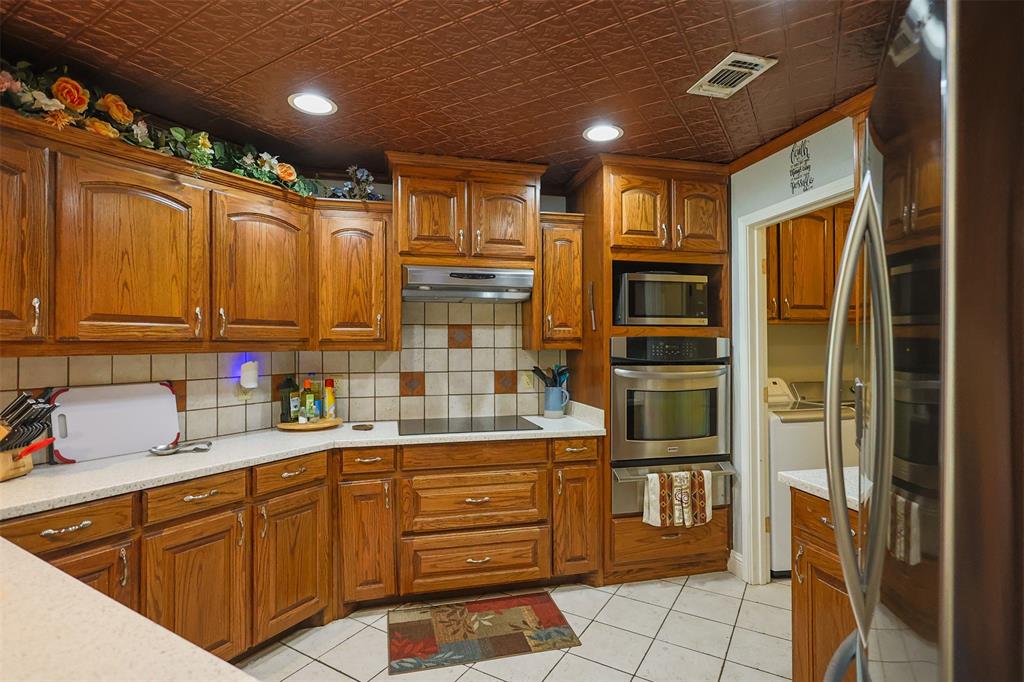 111 Deerfield Road Paradise, TX 76073 - Photo 10 of 39 Kitchen featuring appliances with stainless steel finishes, decorative backsplash, brown cabinetry, recessed lighting, and light tile patterned floors