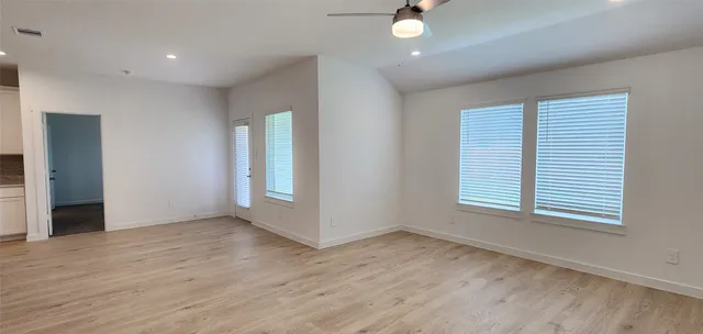 an empty room with wooden floor and windows