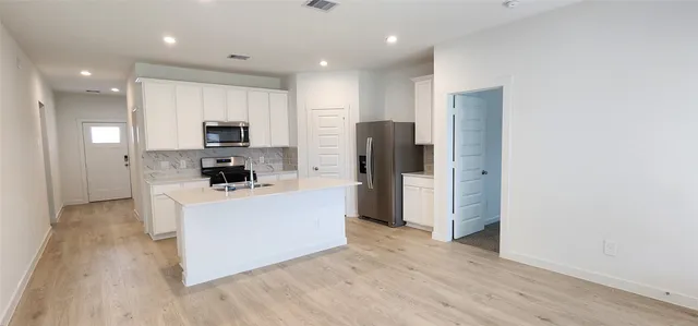 a kitchen with stainless steel appliances a refrigerator and a stove top oven