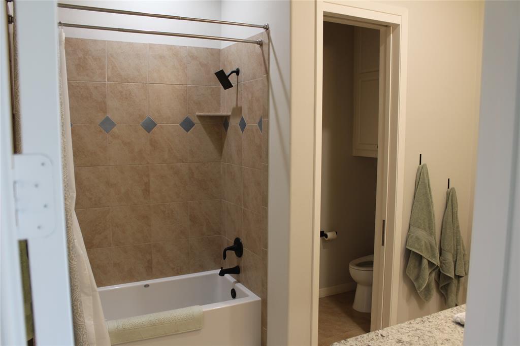333 Renaissance Lane Heath, TX 75032 - Photo 23 of 35 Tub and shower combination featuring beige ceramic tiling with decorative accent tiles, a built-in shower niche, and matte black fixtures